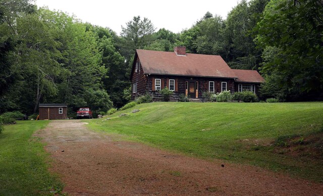 32 Williams Rd, Chelsea, ME 04330 - log home with driveway, a chimney, a storage shed, and a front lawn