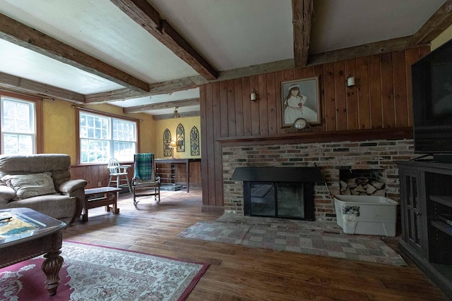 32 Williams Rd, Chelsea, ME 04330 - living room featuring wood walls, beam ceiling, wood finished floors, and a fireplace