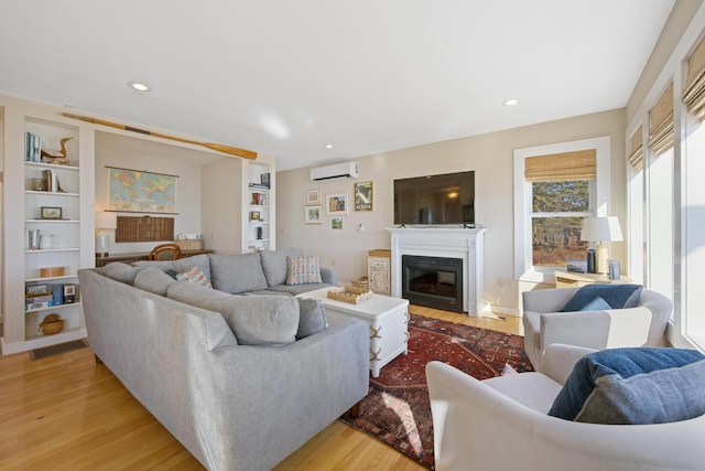 74 Spindle Rd, Ellsworth, ME 04605 - living room with light wood finished floors, built in features, a glass covered fireplace, an AC wall unit, and recessed lighting