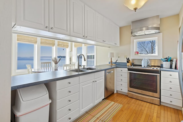74 Spindle Rd, Ellsworth, ME 04605 - kitchen with appliances with stainless steel finishes, wall chimney exhaust hood, light wood-style floors, white cabinetry, and dark countertops