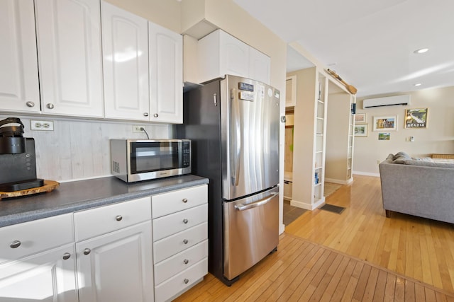 74 Spindle Rd, Ellsworth, ME 04605 - kitchen with a wall unit AC, appliances with stainless steel finishes, light wood-style floors, open floor plan, and dark countertops