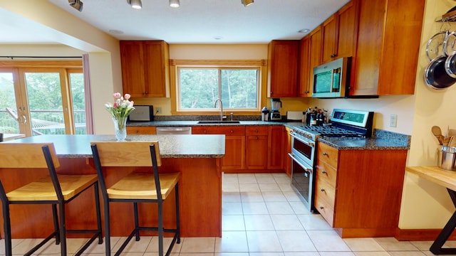 93 Hopkins Rd, Hampden, ME 04444 - kitchen with stainless steel appliances, dark countertops, a kitchen bar, and light tile patterned flooring