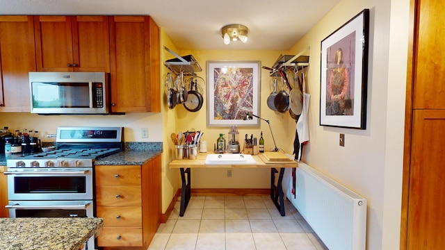 93 Hopkins Rd, Hampden, ME 04444 - kitchen with stainless steel appliances, radiator heating unit, light tile patterned floors, and brown cabinets