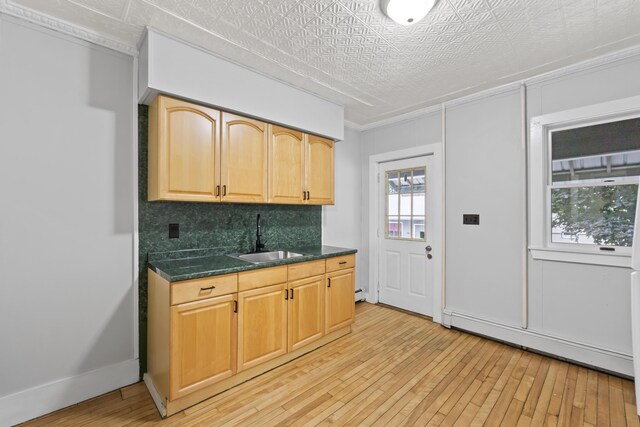 13 Newman St, Lewiston, ME 04240 - kitchen with baseboard heating, light wood-type flooring, backsplash, crown molding, and dark stone counters