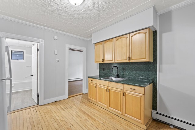 13 Newman St, Lewiston, ME 04240 - kitchen with a baseboard heating unit, freestanding refrigerator, light wood finished floors, baseboard heating, and ornamental molding