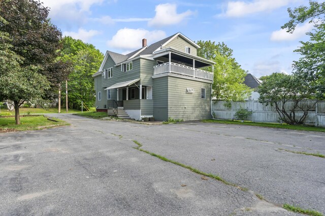 13 Newman St, Lewiston, ME 04240 - view of home's exterior featuring a balcony, a chimney, and asphalt driveway