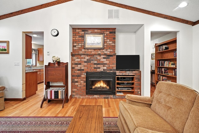 3 Tallwood Rd, Augusta, ME 04330 - living room with lofted ceiling, light wood-style flooring, a brick fireplace, built in shelves, and a textured ceiling