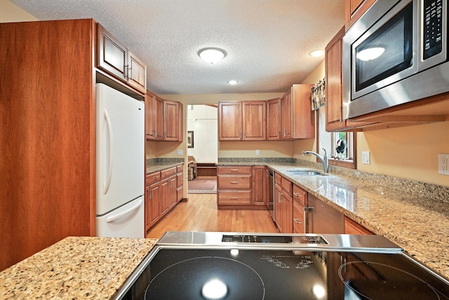 3 Tallwood Rd, Augusta, ME 04330 - kitchen with freestanding refrigerator, stainless steel microwave, a textured ceiling, brown cabinets, and light wood-style flooring