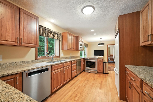 3 Tallwood Rd, Augusta, ME 04330 - kitchen with stainless steel appliances, brown cabinetry, light wood-style floors, a textured ceiling, and light stone counters