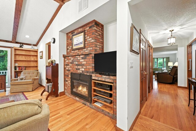 3 Tallwood Rd, Augusta, ME 04330 - living area with a textured ceiling, a brick fireplace, light wood-style flooring, and beamed ceiling