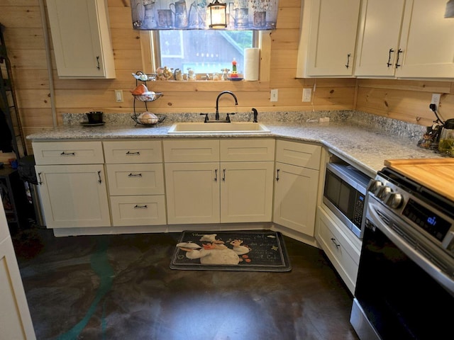 340 Campground Rd, Anson, ME 04958 - kitchen with appliances with stainless steel finishes, wood walls, concrete floors, and white cabinets