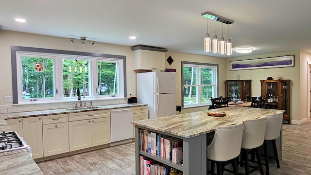 62 Cobb Rd, Stetson, ME 04488 - kitchen with white appliances, light wood-style floors, a breakfast bar area, hanging light fixtures, and a kitchen island