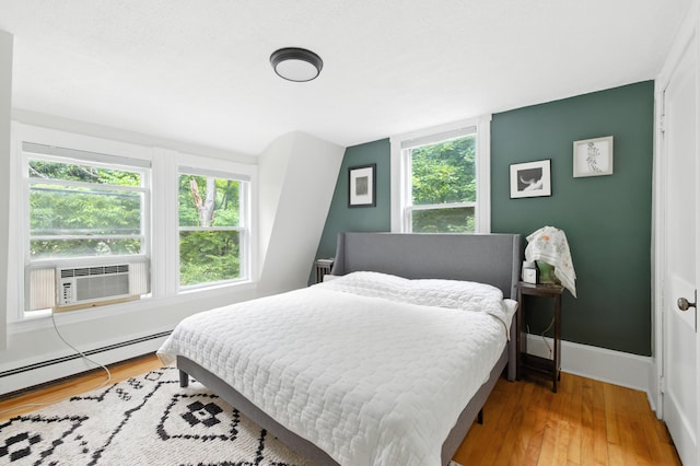 214 S Main St, Auburn, ME 04210 - bedroom with cooling unit, multiple windows, wood finished floors, and a baseboard heating unit