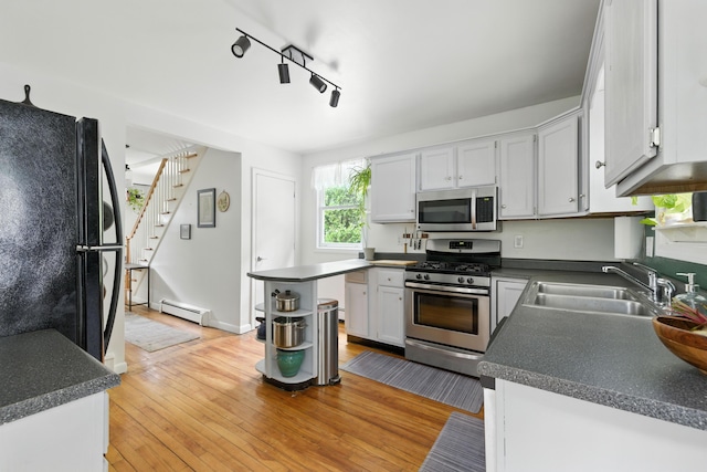 214 S Main St, Auburn, ME 04210 - kitchen with stainless steel appliances, a baseboard radiator, dark countertops, light wood finished floors, and open shelves