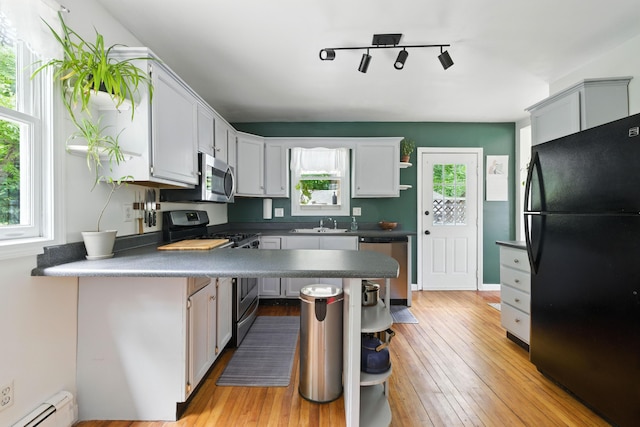 214 S Main St, Auburn, ME 04210 - kitchen featuring stainless steel appliances, open shelves, a baseboard heating unit, dark countertops, and light wood-type flooring