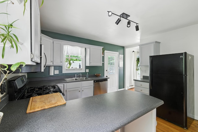 214 S Main St, Auburn, ME 04210 - kitchen with freestanding refrigerator, gas range oven, stainless steel dishwasher, a peninsula, and dark countertops