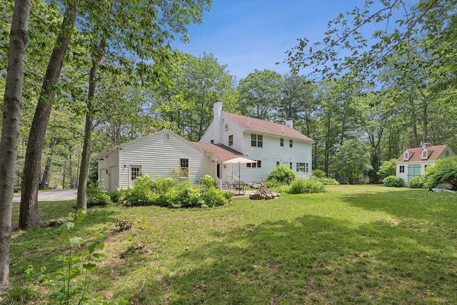 6 Beechwood Ln, Falmouth, ME 04105 - rear view of property featuring a chimney, a yard, driveway, and view of wooded area