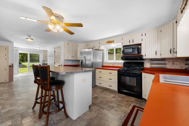 52 Ludden Ln, Lincoln, ME 04457 - kitchen featuring black appliances, stone finish flooring, tasteful backsplash, a ceiling fan, and a kitchen island