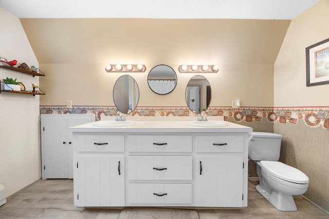 52 Ludden Ln, Lincoln, ME 04457 - full bathroom with lofted ceiling, double vanity, a wainscoted wall, and wood finished floors