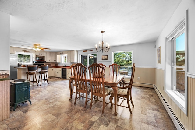 52 Ludden Ln, Lincoln, ME 04457 - dining area featuring stone finish flooring, a baseboard heating unit, a chandelier, a wainscoted wall, and a wood stove