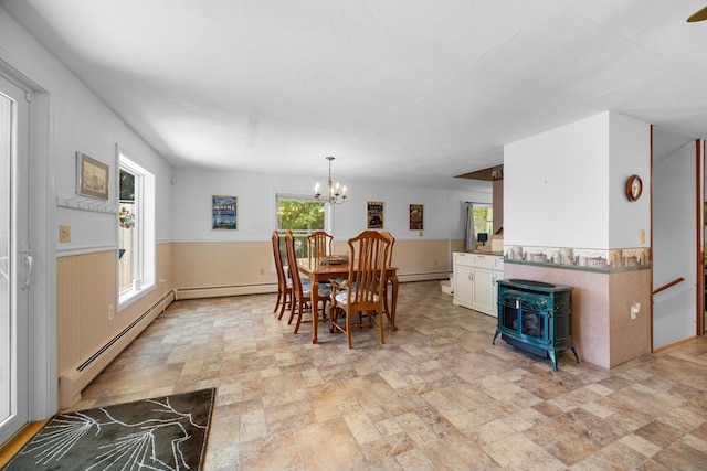 52 Ludden Ln, Lincoln, ME 04457 - dining area featuring stone finish floors, wainscoting, a wood stove, a chandelier, and a baseboard heating unit