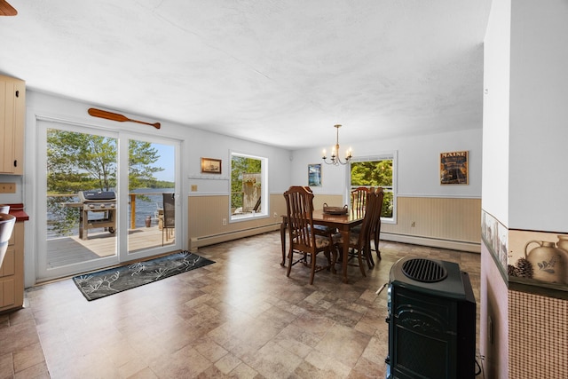 52 Ludden Ln, Lincoln, ME 04457 - dining space with a baseboard radiator, a chandelier, wainscoting, and a wood stove