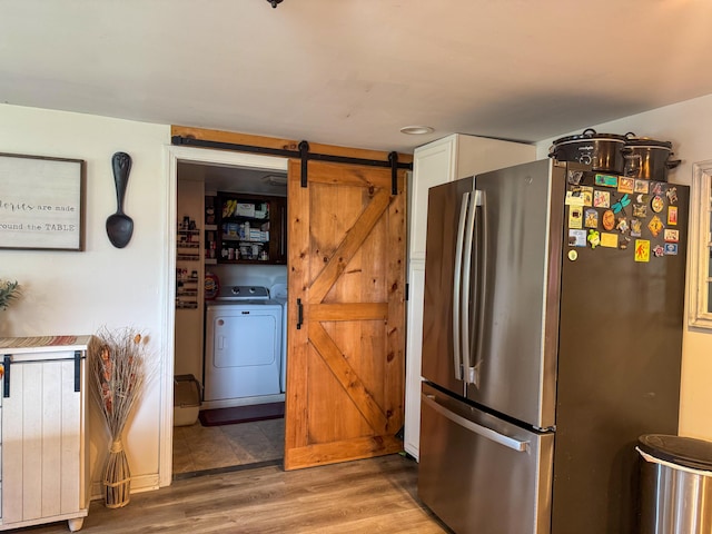 27 Main St, Vassalboro, ME 04989 - kitchen featuring freestanding refrigerator, washer / dryer, a barn door, wood finished floors, and white cabinetry