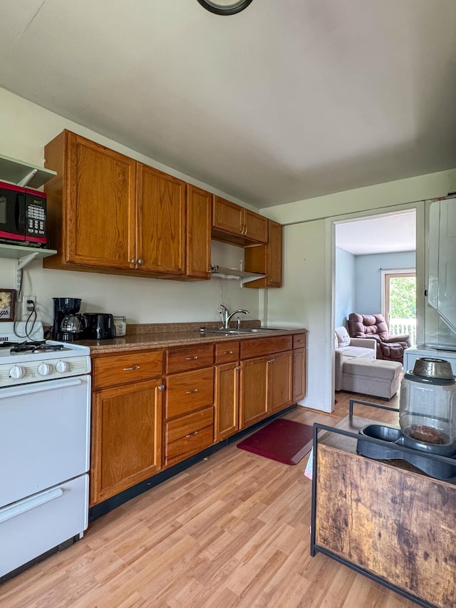 27 Main St, Vassalboro, ME 04989 - kitchen with gas range gas stove, black microwave, open shelves, brown cabinetry, and light wood-type flooring