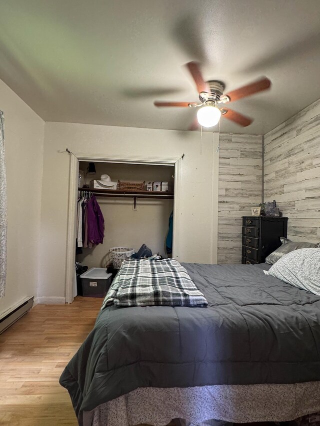 27 Main St, Vassalboro, ME 04989 - bedroom with a closet, wood walls, wood finished floors, a ceiling fan, and a baseboard heating unit
