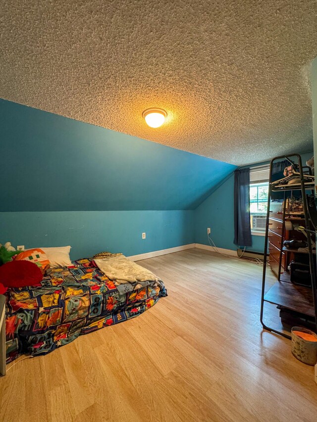 27 Main St, Vassalboro, ME 04989 - bedroom with wood finished floors, lofted ceiling, a textured ceiling, and cooling unit