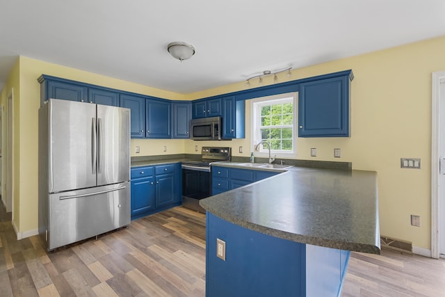 32 Barton Rd, Windsor, ME 04363 - kitchen with stainless steel appliances, dark countertops, a peninsula, blue cabinets, and light wood finished floors