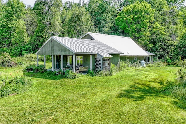 672 Brooks Rd, Knox, ME 04986 - view of front of property with a front lawn, a standing seam roof, a metal roof, a porch, and a view of trees