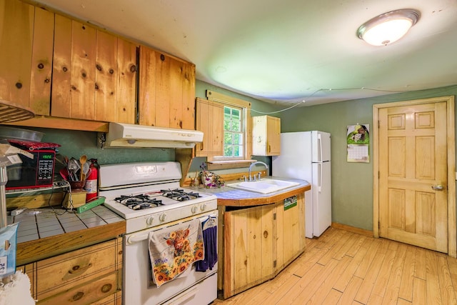 672 Brooks Rd, Knox, ME 04986 - kitchen featuring white appliances, under cabinet range hood, tile countertops, and light wood-type flooring