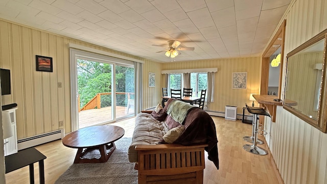 585 N Lubec Rd, Lubec, ME 04652 - living area featuring a baseboard radiator, ceiling fan, light wood-type flooring, and wood walls