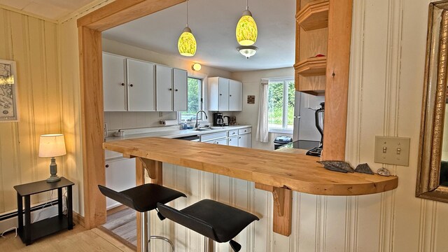 585 N Lubec Rd, Lubec, ME 04652 - kitchen featuring wood counters, white cabinetry, a baseboard radiator, light wood-type flooring, and hanging light fixtures