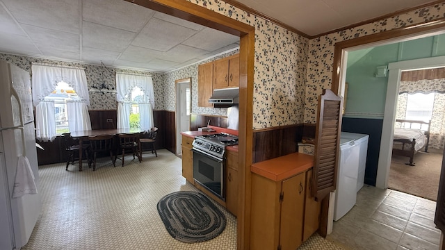269 County Rd, Lubec, ME 04652 - kitchen with wallpapered walls, wainscoting, freestanding refrigerator, stainless steel range with electric cooktop, and extractor fan