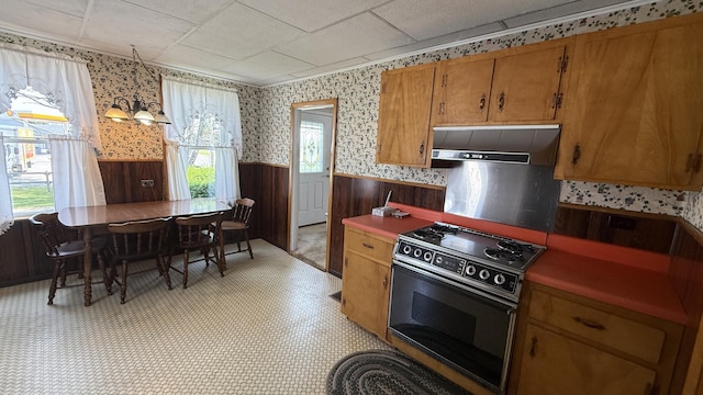 269 County Rd, Lubec, ME 04652 - kitchen with a wainscoted wall, electric range, wallpapered walls, wall chimney exhaust hood, and brown cabinetry