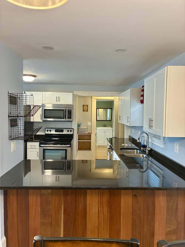 272 Center St, Bangor, ME 04401 - kitchen featuring appliances with stainless steel finishes, white cabinets, dark stone countertops, and a peninsula