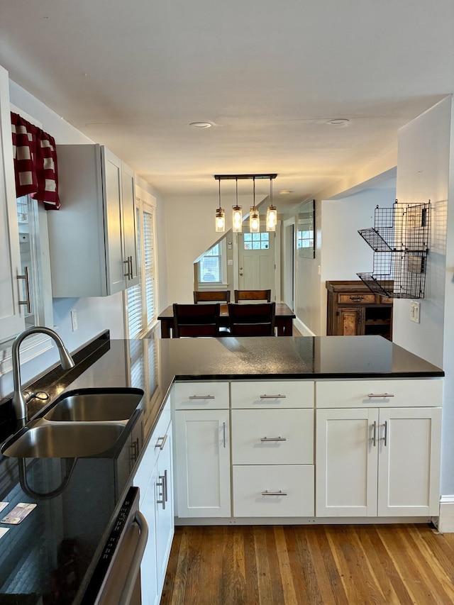 272 Center St, Bangor, ME 04401 - kitchen featuring a peninsula, dark wood-style floors, dark countertops, white cabinets, and hanging light fixtures