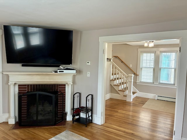272 Center St, Bangor, ME 04401 - living room featuring a baseboard heating unit, wood finished floors, stairway, and a brick fireplace