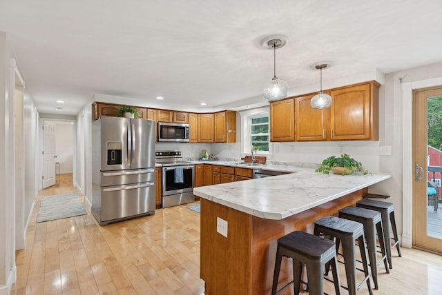 471 Methodist Rd, Westbrook, ME 04092 - kitchen featuring appliances with stainless steel finishes, a peninsula, brown cabinetry, a breakfast bar area, and plenty of natural light