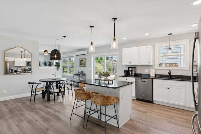 37 Homewood Blvd, Old Orchard Beach, ME 04064 - kitchen with stainless steel appliances, dark countertops, a kitchen bar, an AC wall unit, and recessed lighting