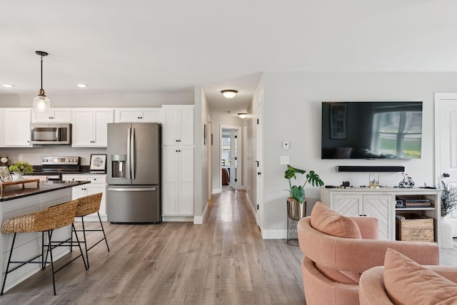 37 Homewood Blvd, Old Orchard Beach, ME 04064 - kitchen featuring appliances with stainless steel finishes, open floor plan, dark countertops, light wood finished floors, and white cabinets