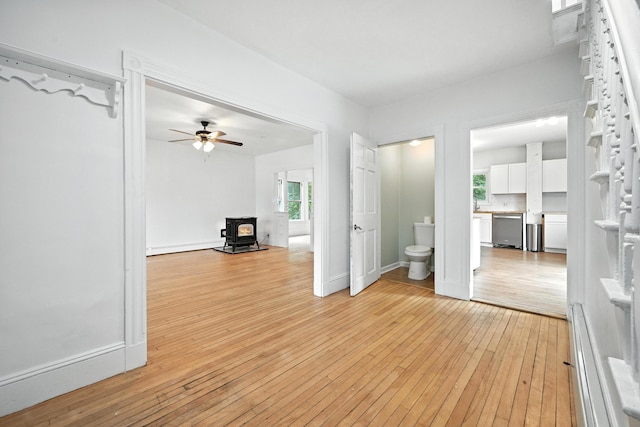 38 Silvermount St, Waterville, ME 04901 - unfurnished living room featuring a wood stove, light wood-style floors, and a ceiling fan