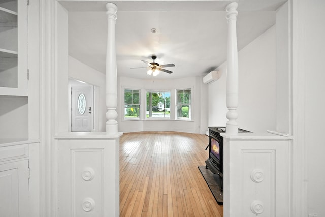 38 Silvermount St, Waterville, ME 04901 - living area featuring a wood stove, an AC wall unit, a ceiling fan, and light wood-style floors