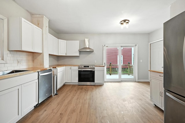 38 Silvermount St, Waterville, ME 04901 - kitchen featuring appliances with stainless steel finishes, wall chimney range hood, light wood-style floors, and white cabinetry