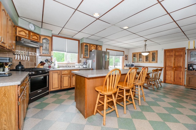 2887 Middle Rd, Sidney, ME 04330 - kitchen featuring freestanding refrigerator, range with gas cooktop, under cabinet range hood, light floors, and healthy amount of natural light