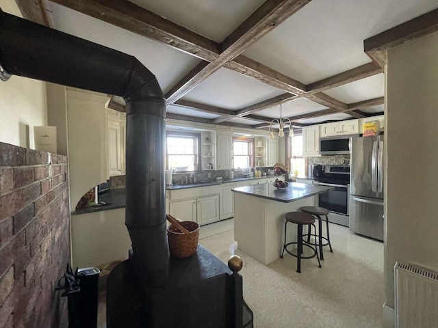 38 Atkinson Rd, Charleston, ME 04422 - kitchen featuring stainless steel appliances, a breakfast bar area, beam ceiling, a kitchen island, and dark countertops
