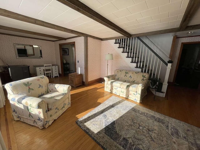 38 Atkinson Rd, Charleston, ME 04422 - living area with wallpapered walls, wood finished floors, beam ceiling, and stairs