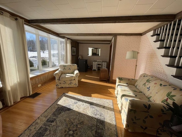 38 Atkinson Rd, Charleston, ME 04422 - living room with hardwood / wood-style floors, beam ceiling, stairs, and wallpapered walls